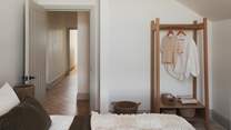 An open wardrobe and additional chest of drawers provide ample storage