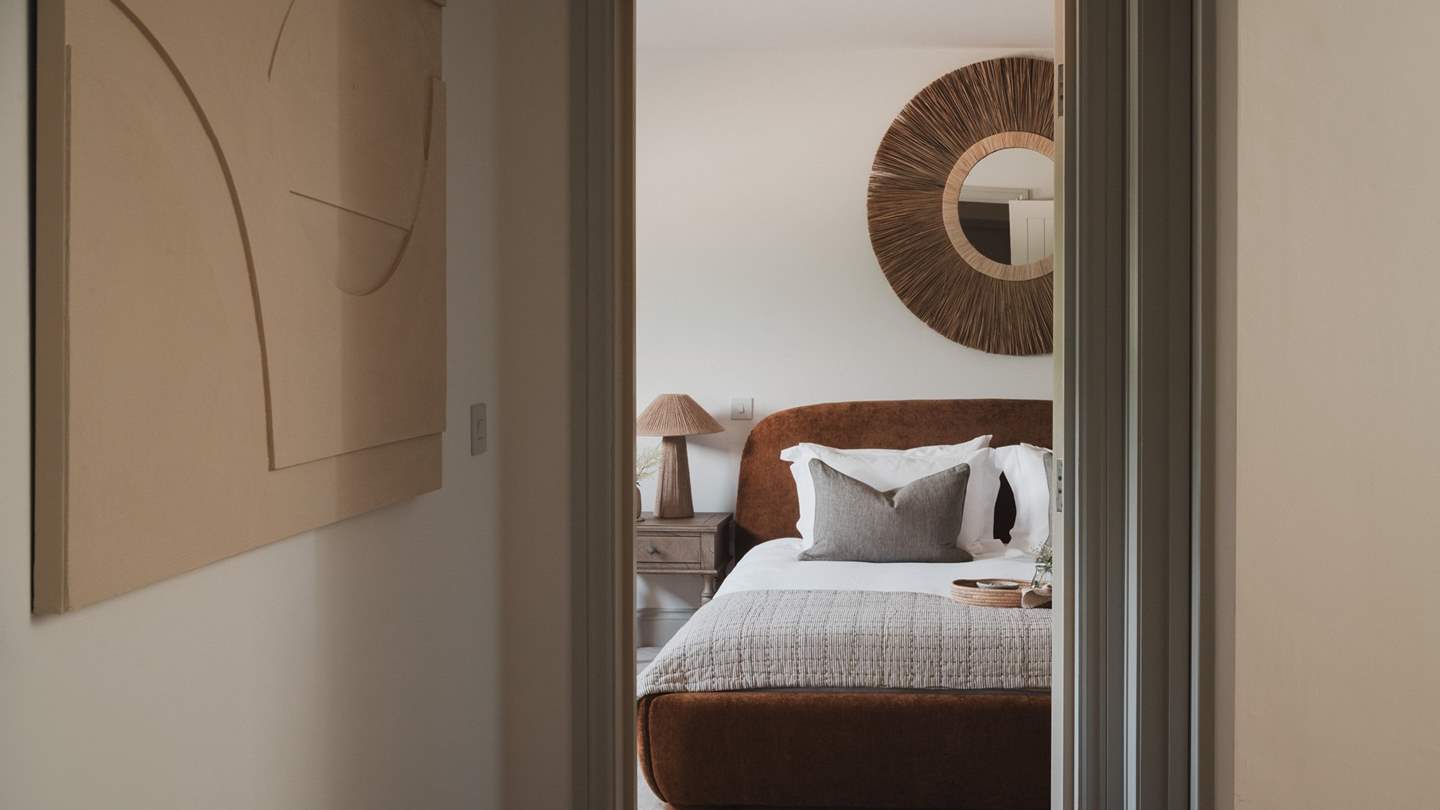 Dressed in warm, earthy tones, it is complemented by a statement boho-style mirror overhead 