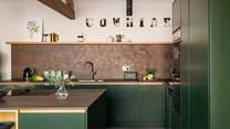 Adorned in forest greens and copper tones, the kitchen features everything you need for preparing feasting dishes