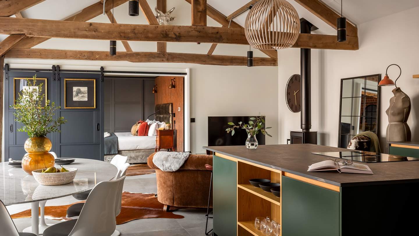 Framed by exposed beams and brickwork, this characterful space is dressed with sumptuous furnishings and antique touches