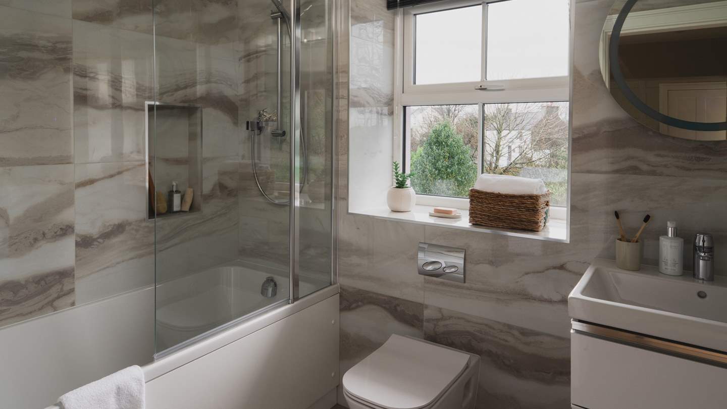 The family bathroom is complete with a bathtub and an overhead shower