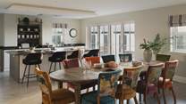 Set between the kitchen and living area is the dining space, where a wooden table and ten chairs offer a stylish setting for mealtimes together at any hour