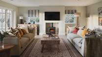 Two neutral-toned sofas are perfectly positioned in front of the electric wood burning stove and Smart TV