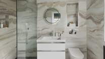 Adjacent is the en suite shower room, featuring striking quartz effect tiles and a walk-in shower with a rainfall head