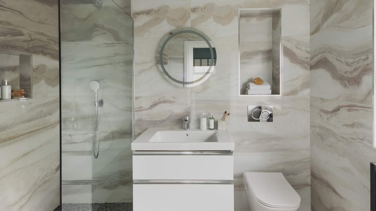 Adjacent is the en suite shower room, featuring striking quartz effect tiles and a walk-in shower with a rainfall head