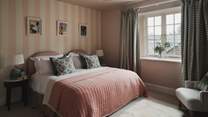 The fifth bedroom is framed by a playful striped backdrop in gentle blush hues