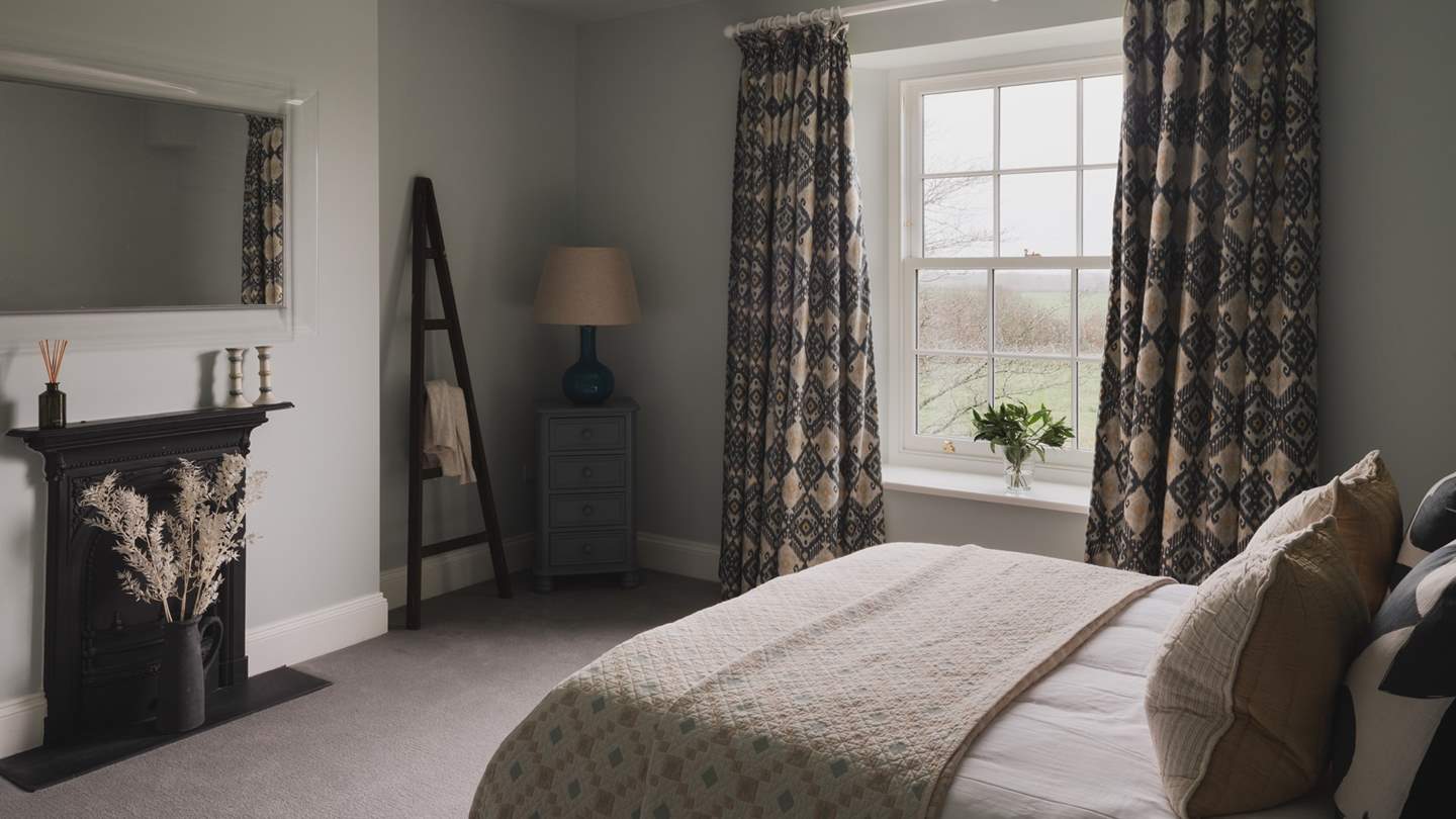 A large mirror rests above the feature fireplace, accompanied by a chest of drawers and a hanging ladder