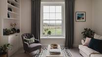 Wwo plush sofas in soft neutral tones and an armchair position perfectly beside a large sash window