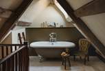 A stunning olive-green, freestanding rolltop bathtub resides for bubble-topped soaks