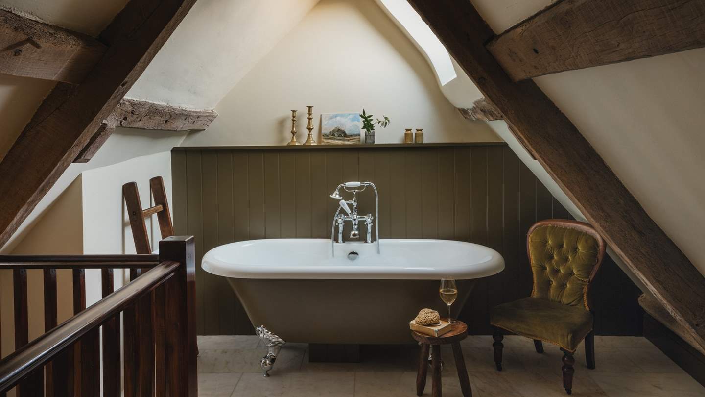 A stunning olive-green, freestanding rolltop bathtub resides for bubble-topped soaks