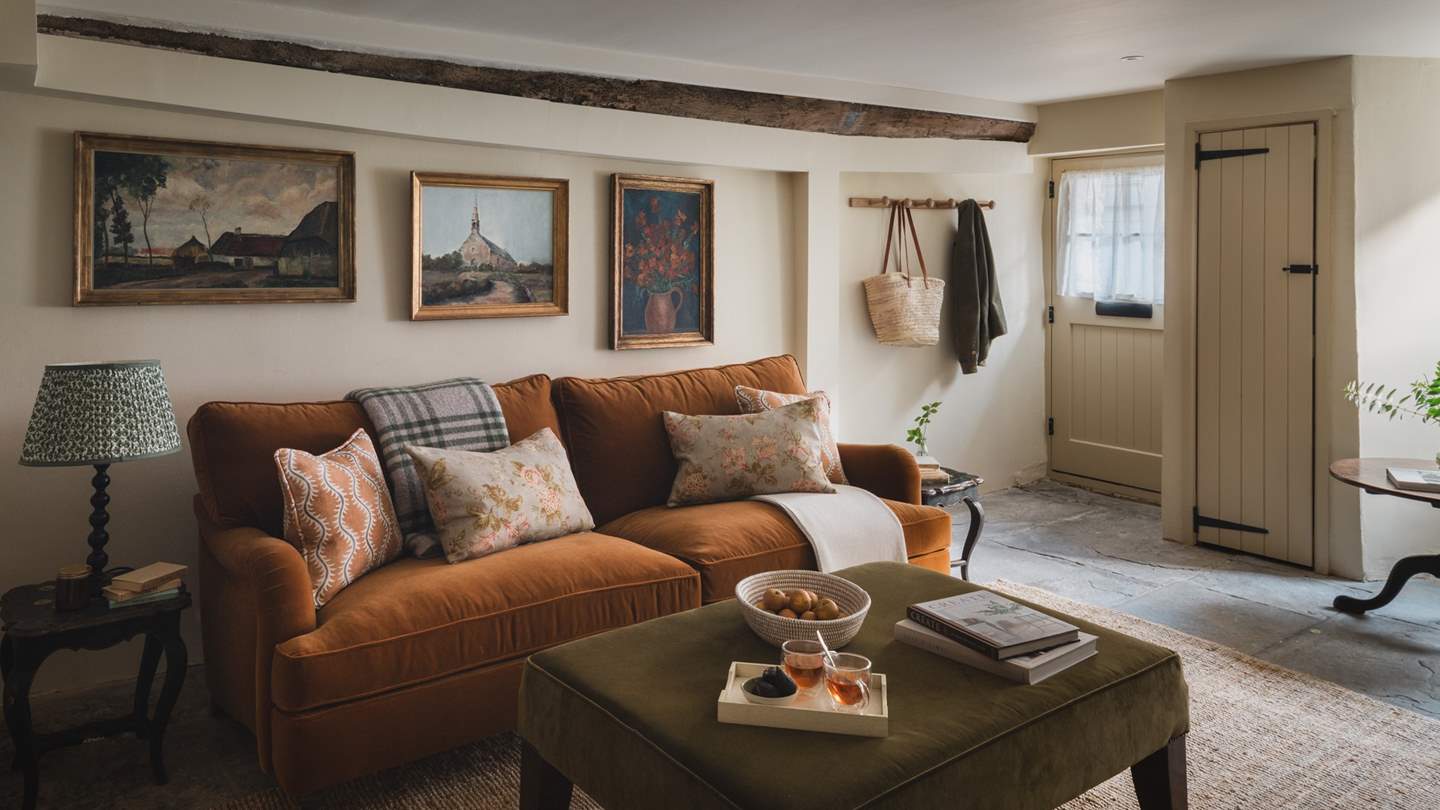 The antique art-adorned cosy living room features beautiful lime plaster, slate flagstones, and rustic wooden beams - a heavenly space to unwind