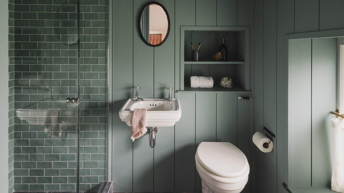 Uncover the charming blue-hued en suite bathroom with charcoal limestone tiles and underfloor heating, complete with a spacious, walk-in rainfall shower