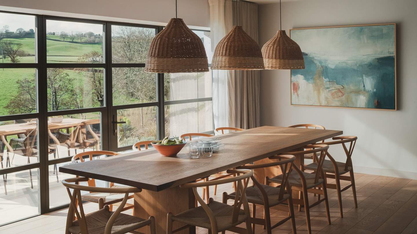 Illuminated by handwoven willow hanging lamps, the grand dining table for eight proposes a fabulous place to dine for mid-morning pastries and sunlit suppers