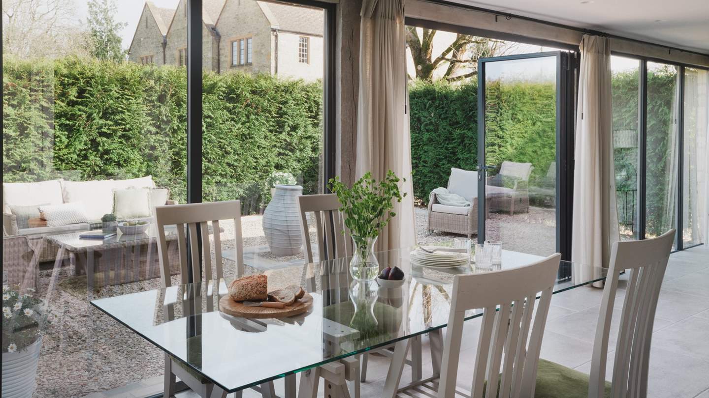 Floor to ceiling bi-fold doors frame the open plan living, kitchen, and dining space