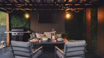A festoon-lit, enclosed seating area awaits with a table and chairs, gas barbecue and wood pellet freestanding heater - there’s also a TV for cinematic evenings together
