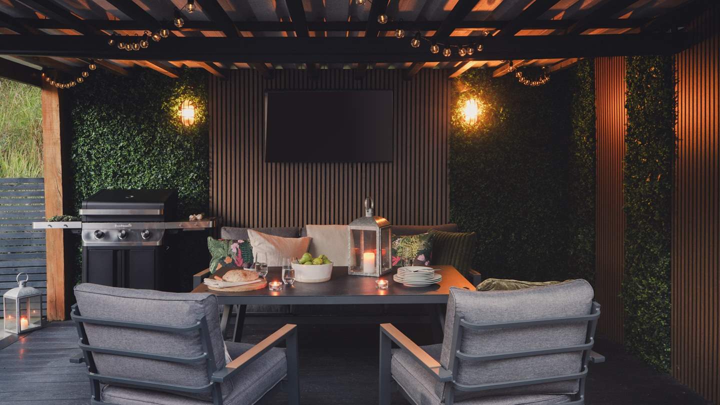 A festoon-lit, enclosed seating area awaits with a table and chairs, gas barbecue and wood pellet freestanding heater - there’s also a TV for cinematic evenings together