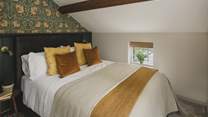 The second bedroom features elegant William Morris Pimpernel print wallpaper and rich tones