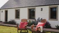 Four wooden lounging chairs can be found in the garden