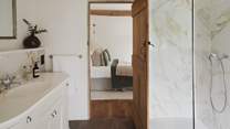 An ensuite bathroom proposes serene self-care rituals with marble hues and a walk-in shower