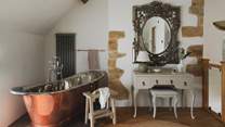 A vintage dressing table sits below an ornate, French giltwood-style mirror