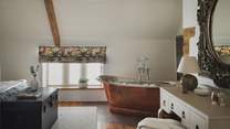 Beneath characterfully sloping ceilings and exposed beams awaits the copper rolltop bathtub