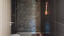 Opposite the third bedroom, a shower room in charcoal tones awaits, featuring a generous rainfall shower
