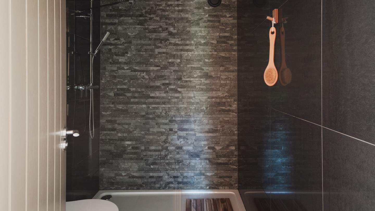 Opposite the third bedroom, a shower room in charcoal tones awaits, featuring a generous rainfall shower