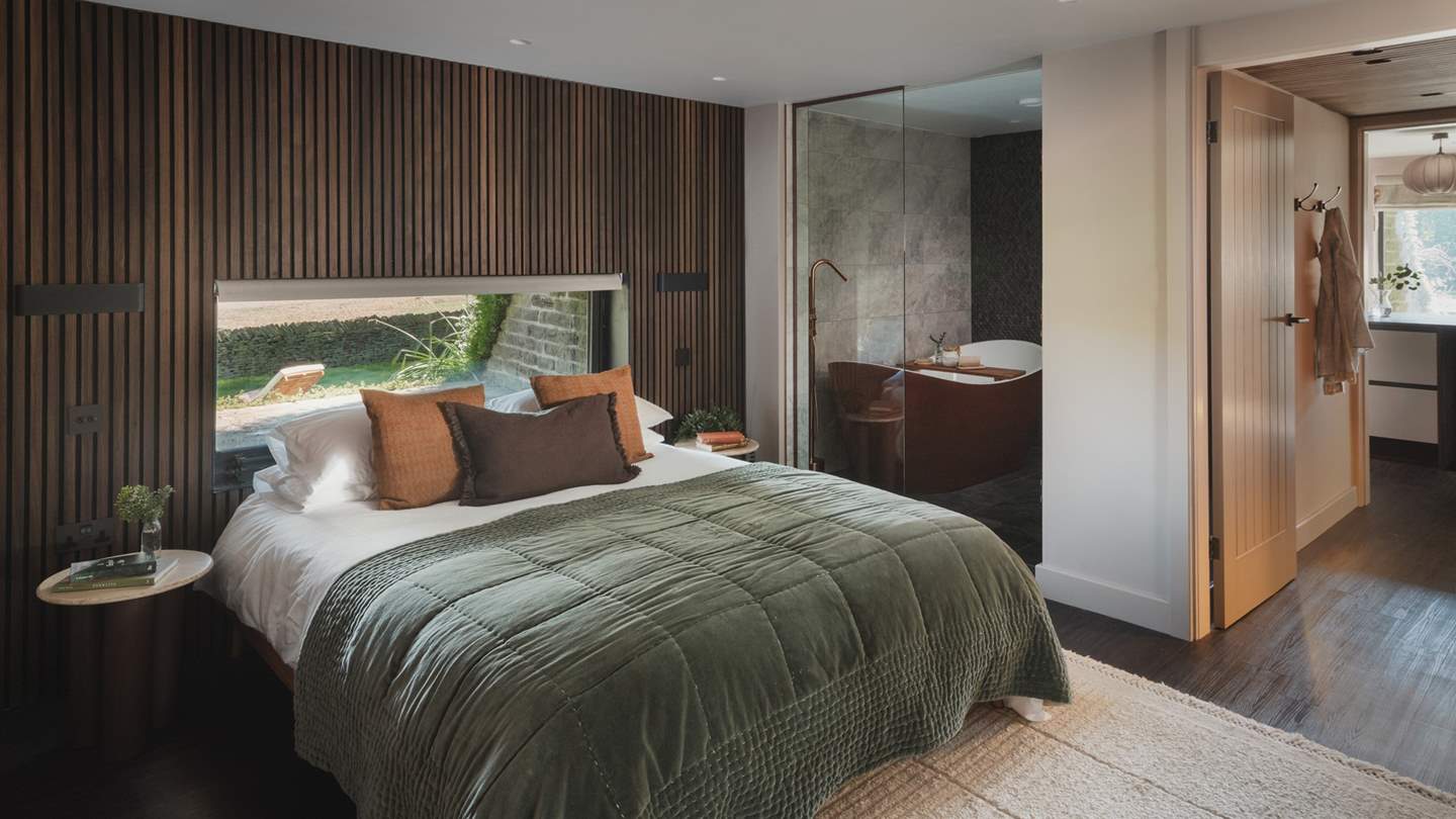Decorated with contemporary panelling in deep oak hues, a king-size bed rests at the heart of the first bedroom