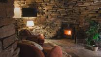 Two armchairs rest before a wood-burning stove, promising a serene setting for fireside tipples