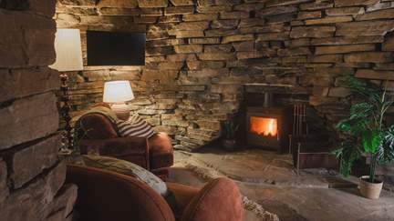 Two armchairs rest before a wood-burning stove, promising a serene setting for fireside tipples