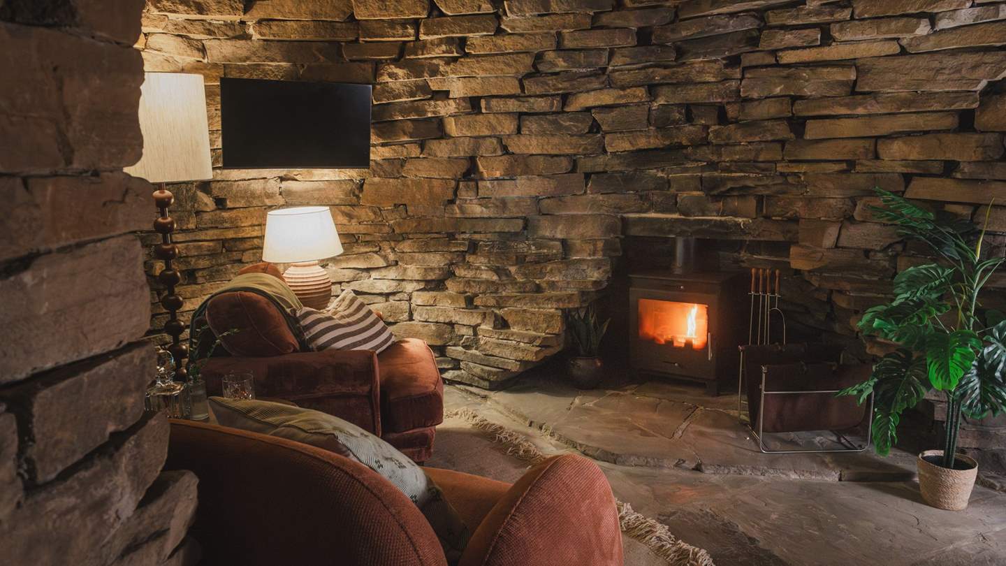 Two armchairs rest before a wood-burning stove, promising a serene setting for fireside tipples