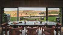 A dining table is elegantly placed before expansive sliding doors that unveil a scene of total tranquillity