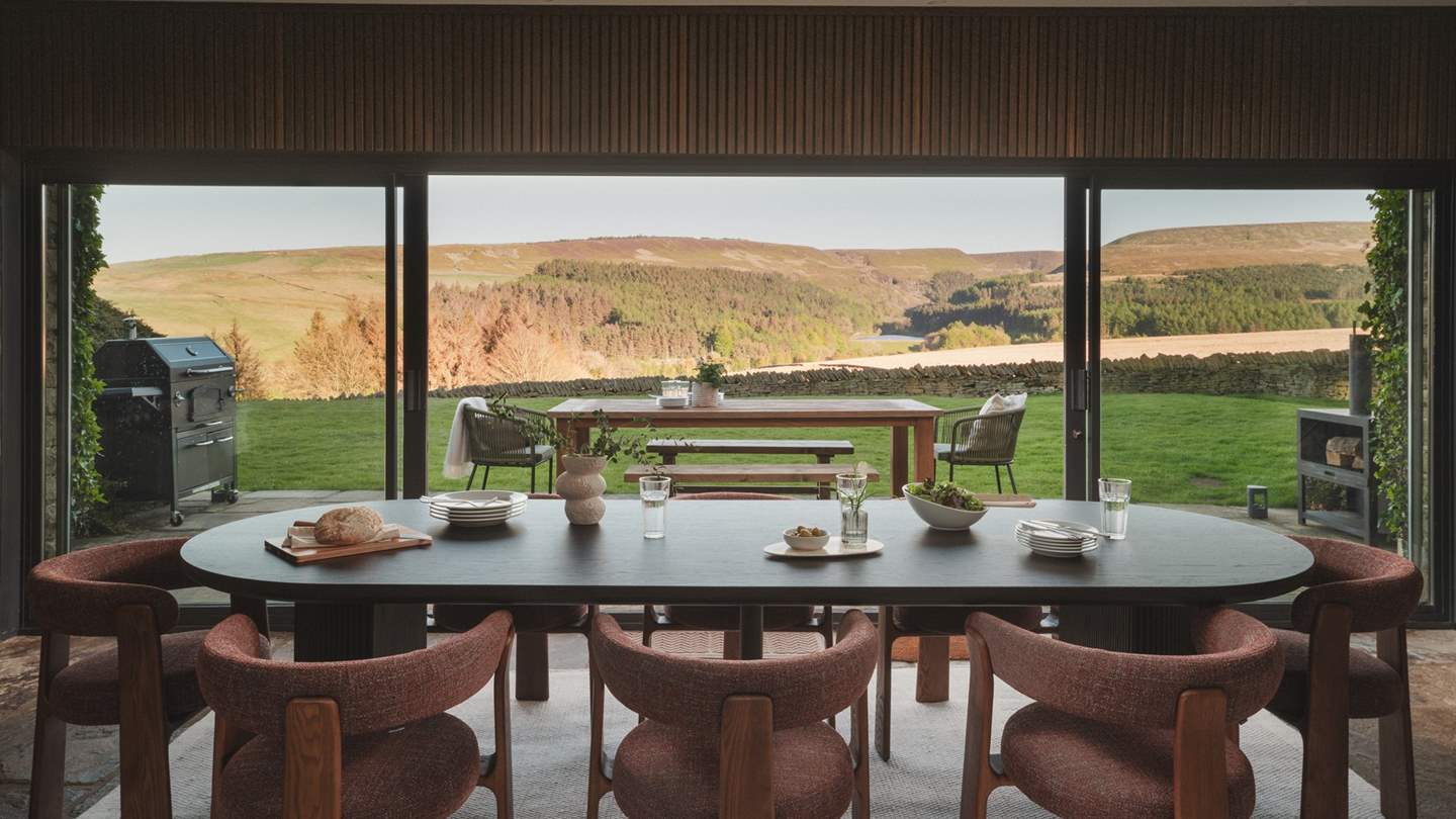 A dining table is elegantly placed before expansive sliding doors that unveil a scene of total tranquillity