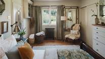 Vintage artwork adorns the walls, while antique mirrors and an elegantly upholstered Victorian nursing chair complete the scene of timeless perfection. 