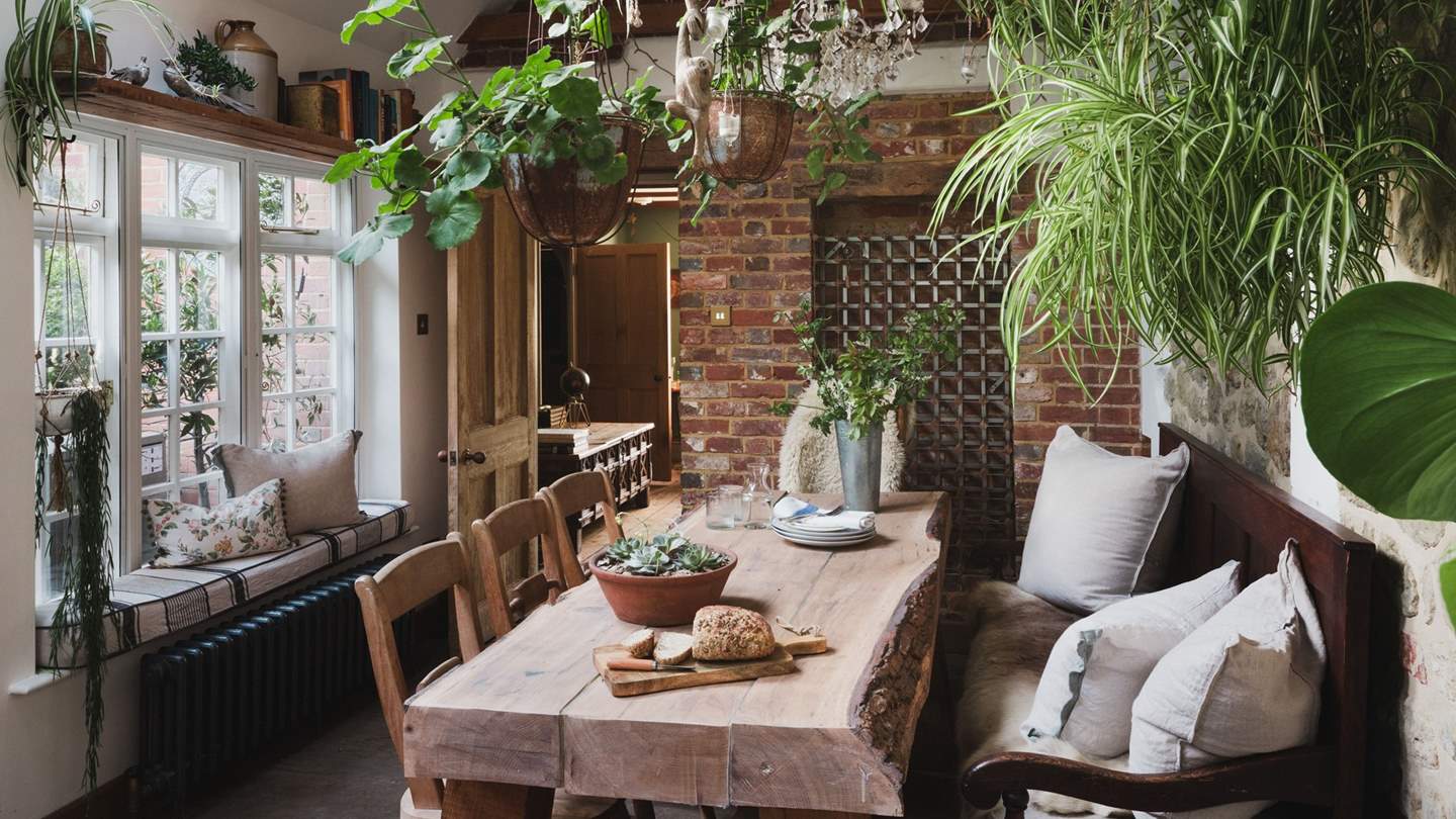 At one side, greenery drapes from rustic beams above a bespoke oak dining table
