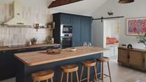 At the centre, an oak-topped kitchen island is complemented by four stools