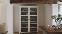At the far side of the room, a White Company display cabinet showcases an elegant collection of glassware and crockery