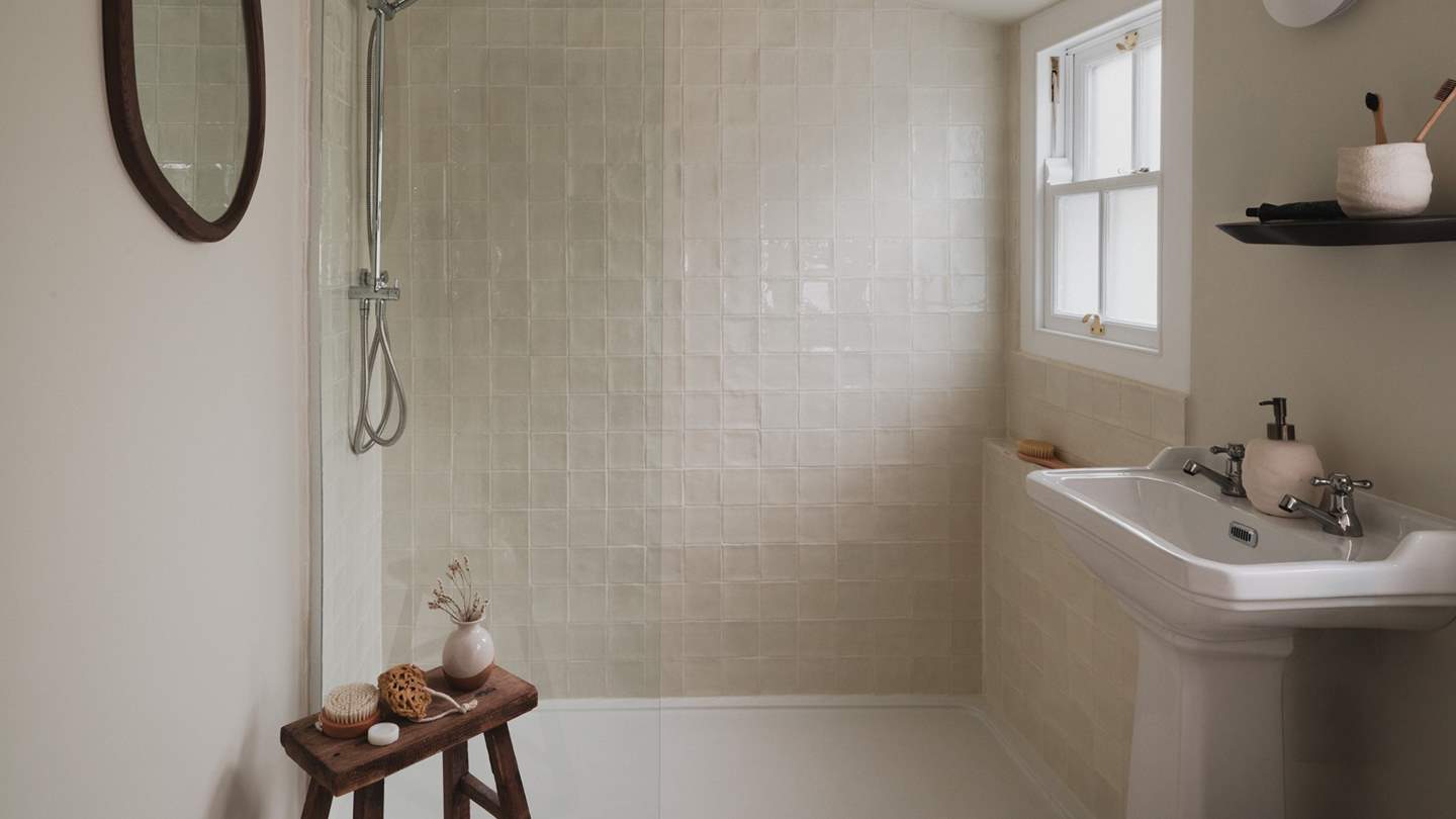 A spacious walk-in shower is adorned with creamy Zeligge tiles