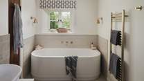 Adjoining this bedroom is an ensuite bathroom, complete with a bath