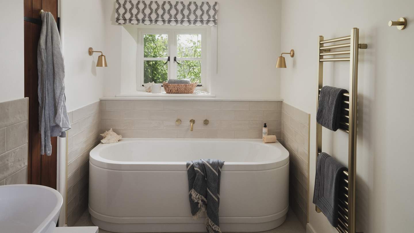 Adjoining this bedroom is an ensuite bathroom, complete with a bath
