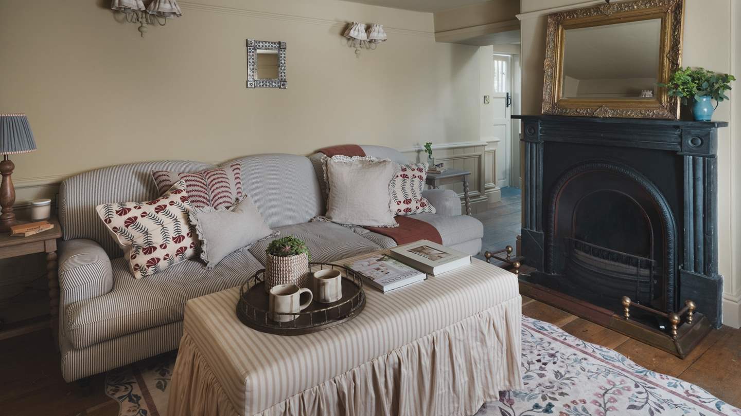 A blue pinstripe sofa rests alongside a frilly footstool
