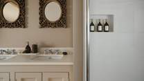Alongside a freestanding bathtub is a luxurious walk-in shower with a rainfall head