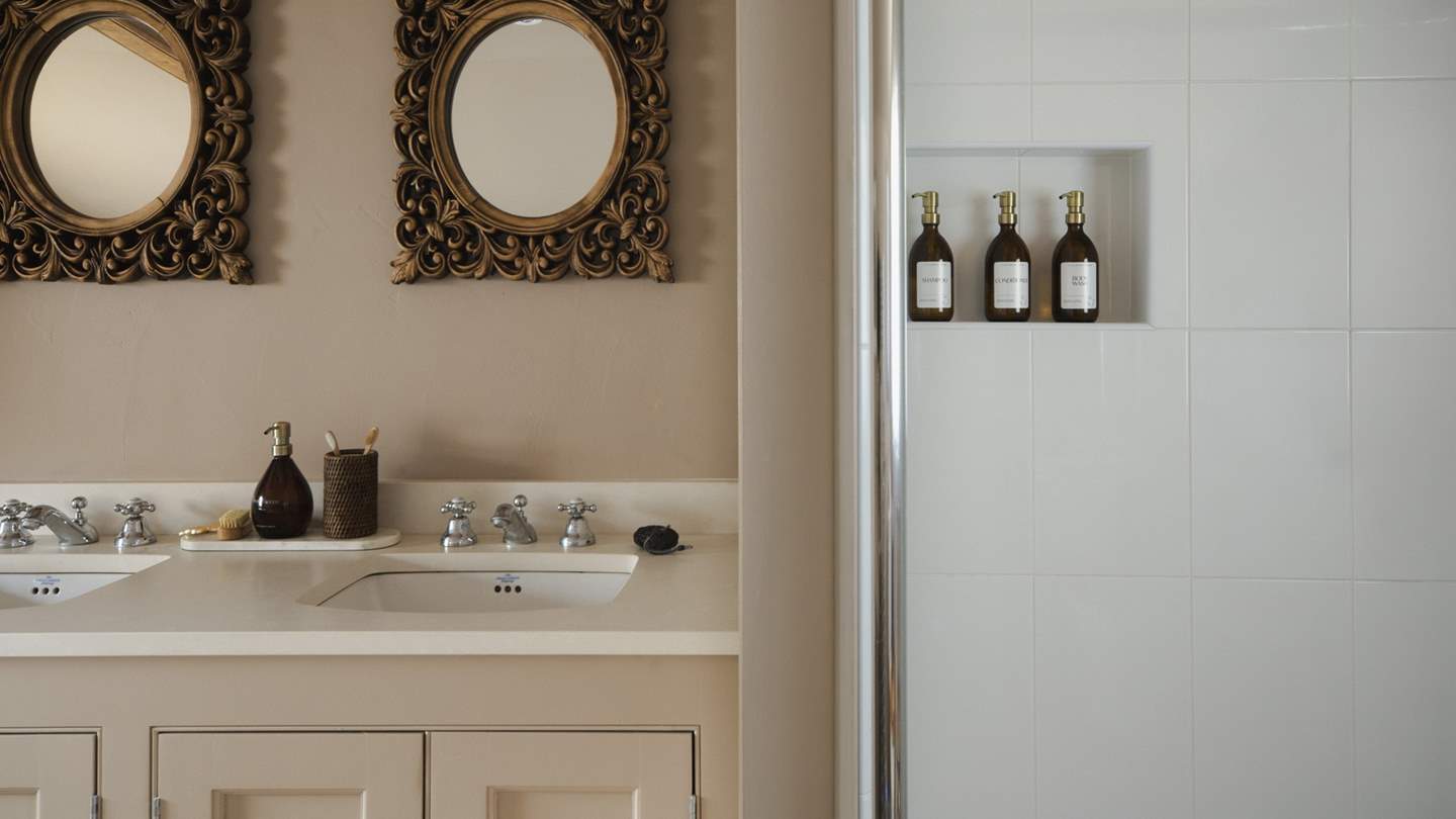 Alongside a freestanding bathtub is a luxurious walk-in shower with a rainfall head