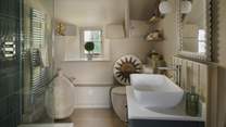 On the top floor resides the sumptuous family bathroom, where glossy emerald, green tiles adorn the walk-in shower 