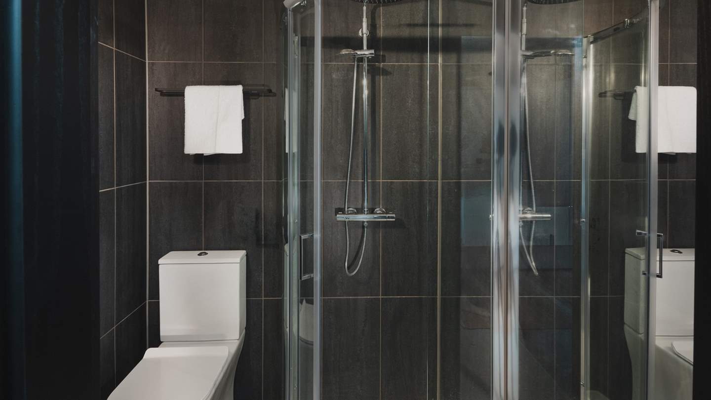 An ensuite bathroom with a bath and overhead shower offers comfort and convenience for self-care rituals throughout the day