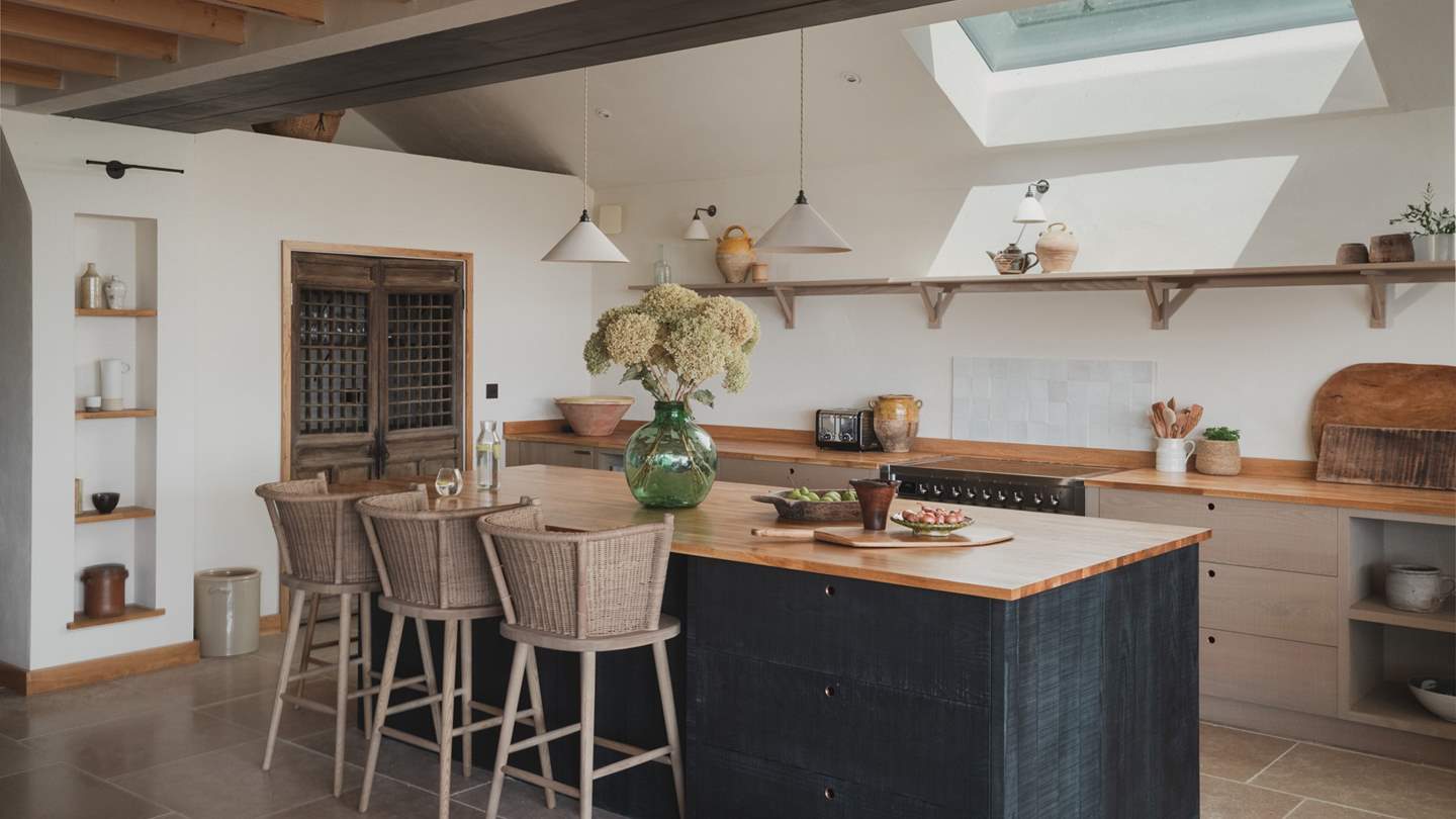 Generous oak worktops, dark textured cabinetry and a kitchen island offer a canvas for curated plates and popped corks. 