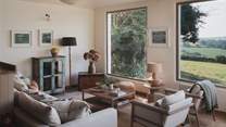 Take a seat on the sofa adorned with cosy cushions and throws or one of the two armchairs