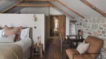 The first bedroom features a super king bed, and two comfortable armchairs for serene repose