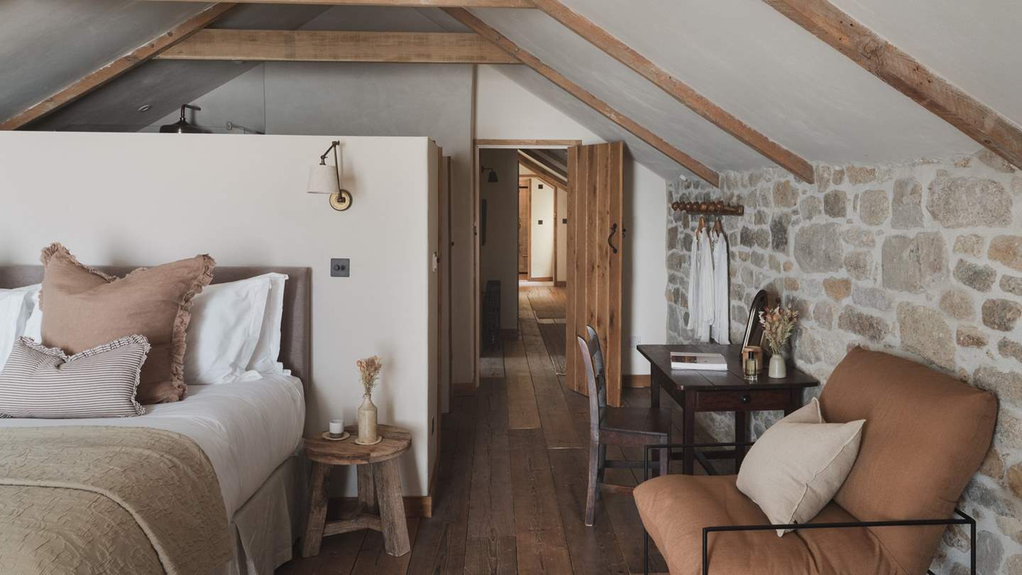 The first bedroom features a super king bed, and two comfortable armchairs for serene repose