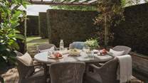 A yew-fringed patio welcomes alfresco dining under blue skies